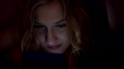 Smartphone addiction. Instead of sleeping at night, a young woman browses something on a mobile