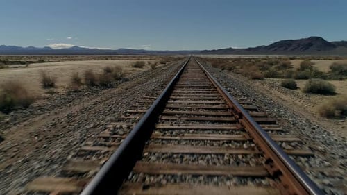 Schnelle, niedrige Luftaufnahme, vorwärts auf geraden Eisenbahnschienen in der Wüste