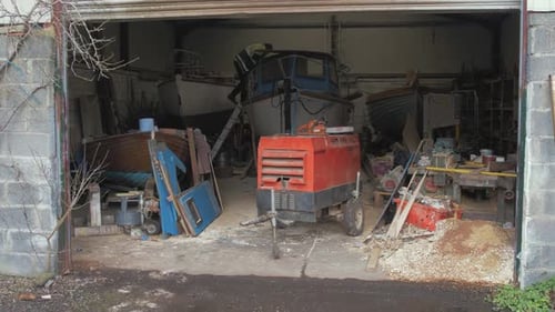 Um construtor naval sobe a bordo de um barco em seu galpão