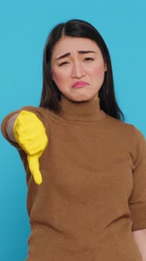 Woman Giving Thumbs Down Wearing Yellow Cleaning Glove