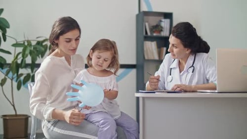 Doctor Talking to Mother and Child in Office