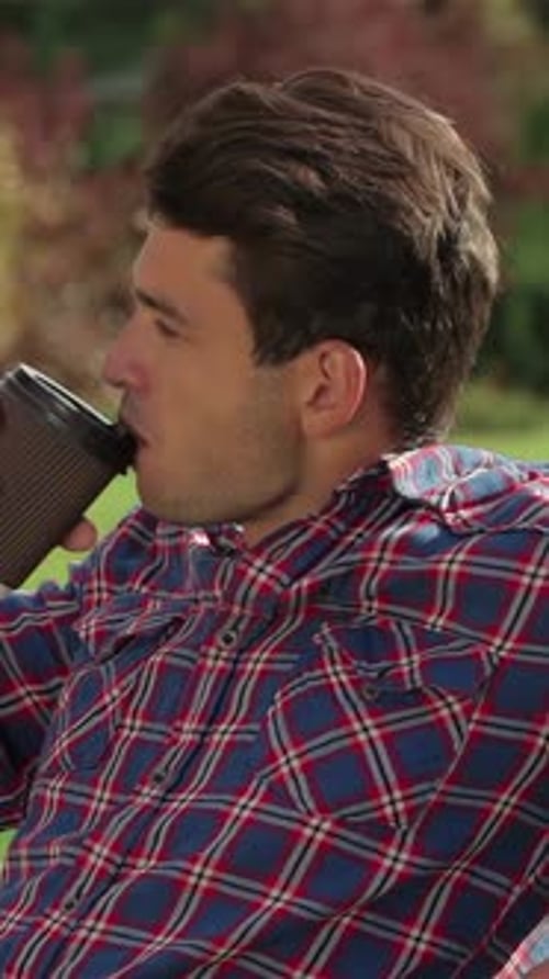 Relaxed Male Savoring Coffee in a Sunlit Park