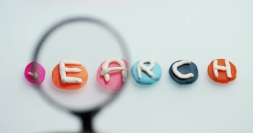 Magnifying Glass Over Clay Letters Spelling Search