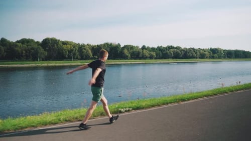Athletic Man Warming Up Along a Lakeside Path