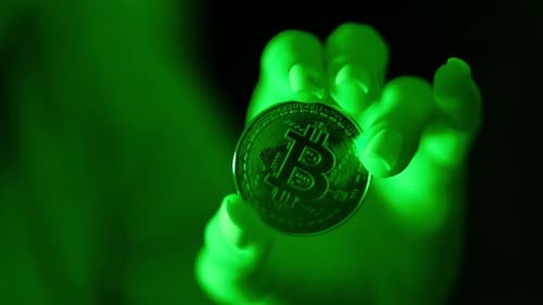 Bitcoin Coin in Green Light Close Up - Digital Economy and Risky Finance