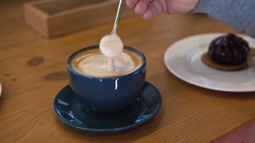 Latte Stirred with Spoon next to Dessert