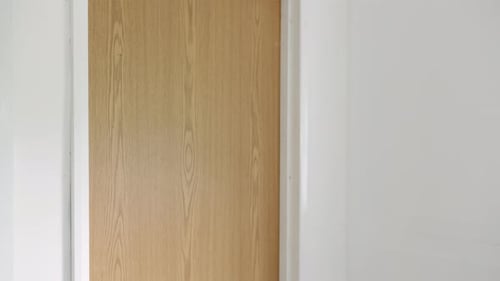 A mature businessman knocking on a door before entering an office. The man opens the door after the