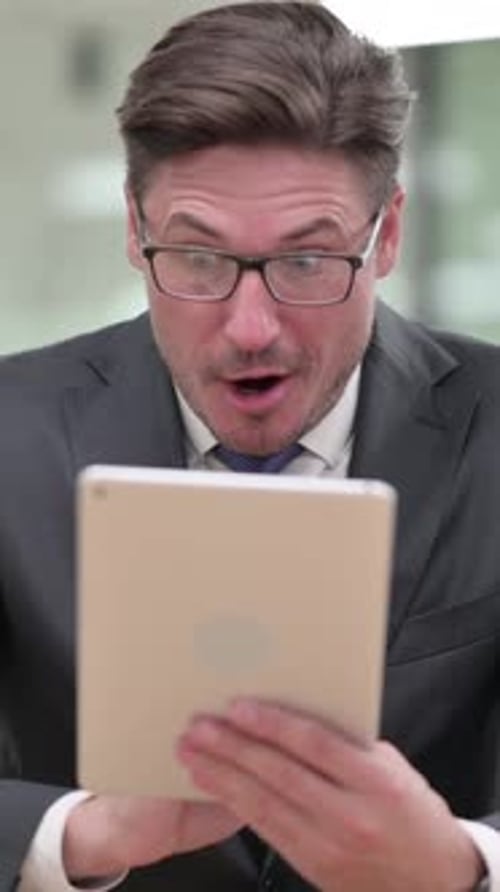Excited Businessman Reacting to Good News on Tablet