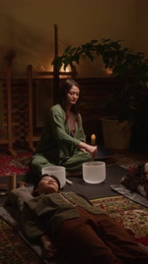 Female Sound Healing Master Playing Singing Bowls for Meditating Guests