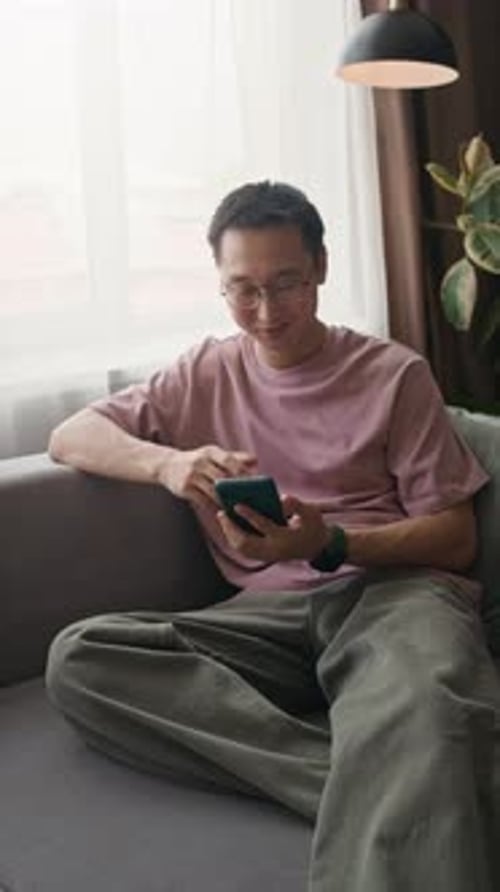 Man Relaxing on Sofa While Using Phone