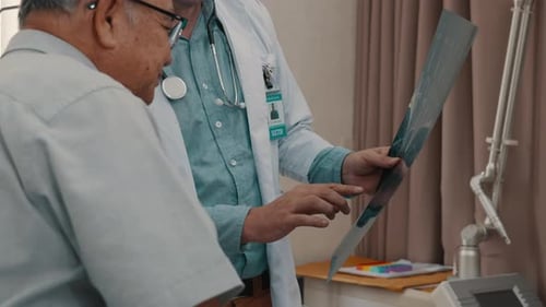 Male doctor explaining x-ray report to senior patient in medical practice.