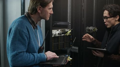 Data Center Technicians Inspecting Network Cables in Server Infrastructure