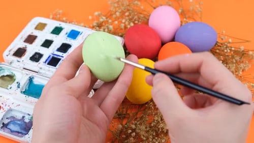 Hands Painting Easter Egg with Paintbrush Close Up
