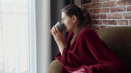 Woman Relaxing Indoors by Window With Mug