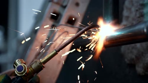 Arbeiter verwendet ein Schweißgerät zum Schweißen von Metallrohren in der Anlage, Nahaufnahme, professioneller Schweißer
