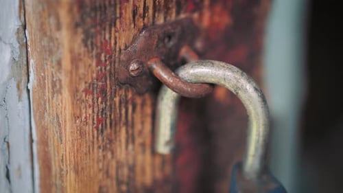 Detail macro shot of an old rusty lock. Closeup of an unlocked antique metal padlock on wooden door