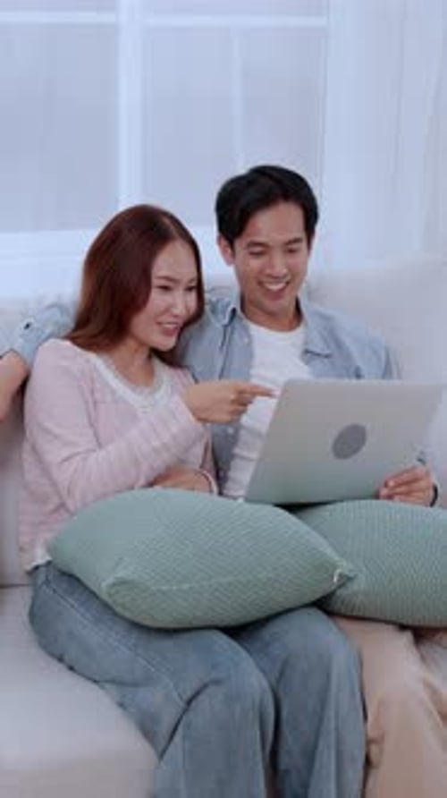 Smiling Couple Relaxing at Home with Laptop