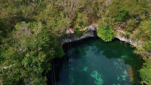 Aerial view of a beautiful Mayan cenote without people. Natural pool of turquoise water surrounded b