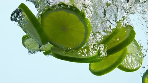 Lime Slices Falling into Refreshing Water