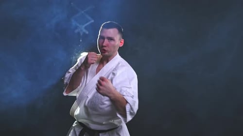 Martial Artist Punching and Kicking in Dark Studio