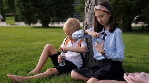 School Children Resting Barefoot in City Park on Grass
