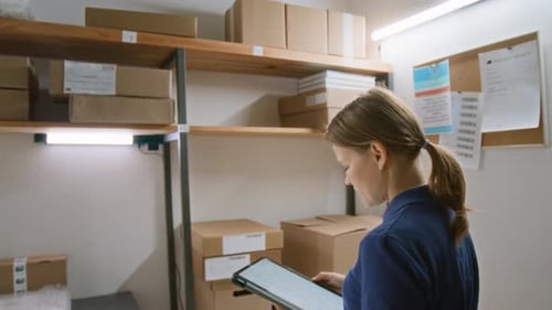 Caucasian Woman Scanning Packages on Racks at Express Delivery Company