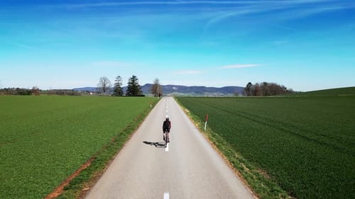 Man cycling on empty asphalt road at countryside at sunny day
