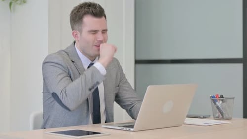 Young Adult Coughing in Office While Working