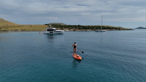 Woman Standup Paddleboarding Near The Yacht In Kornati Island, Croatia. - aerialshot