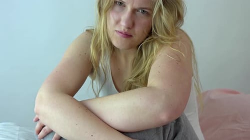 Deprimierte weinende Frau sitzt auf dem Bett und weint. Die Frau empfindet emotionale und psychische Schmerzen,