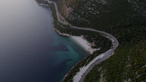 Aerial view of beach, mountain, and road at sunset, Croatia.