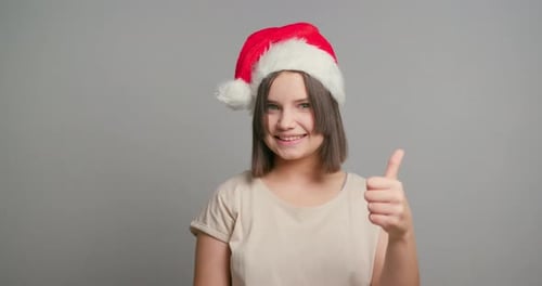 Smiling Teen Wearing Santa Hat Giving Thumbs Up