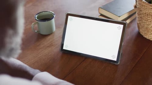 Senior african american man sitting at table and using tablet with copy space, slow motion