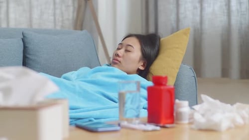 Gros plan d'une femme asiatique malade avec une couverture dormant sur un canapé dans le salon à la maison