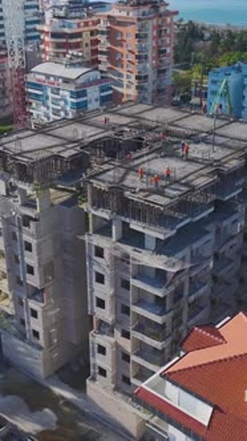 Vertical Video of a Group of Construction Workers Placing Concrete Blocks and Adjusting Metal