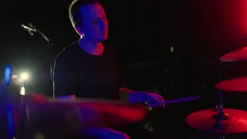 Man Playing Drums with Red and Blue Lighting