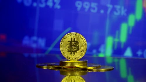 Golden Bitcoin Coins on Reflective Surface with Stock Data