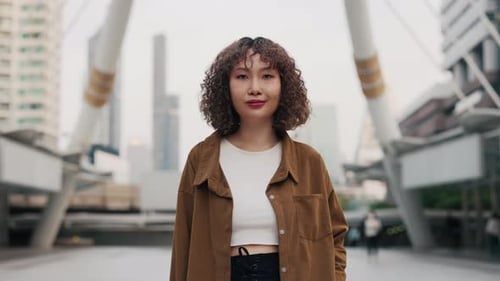 Smiling Beautiful Girl Of Asian Appearance Standing On The Street And Posing For Camera