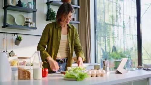 Woman Prepares Salad While Following Recipe on Tablet