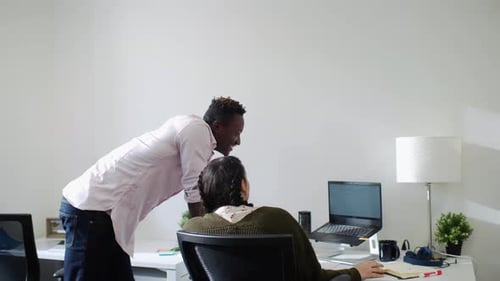 Jeunes collègues de travail collaborant sur un ordinateur portable dans un environnement de bureau moderne