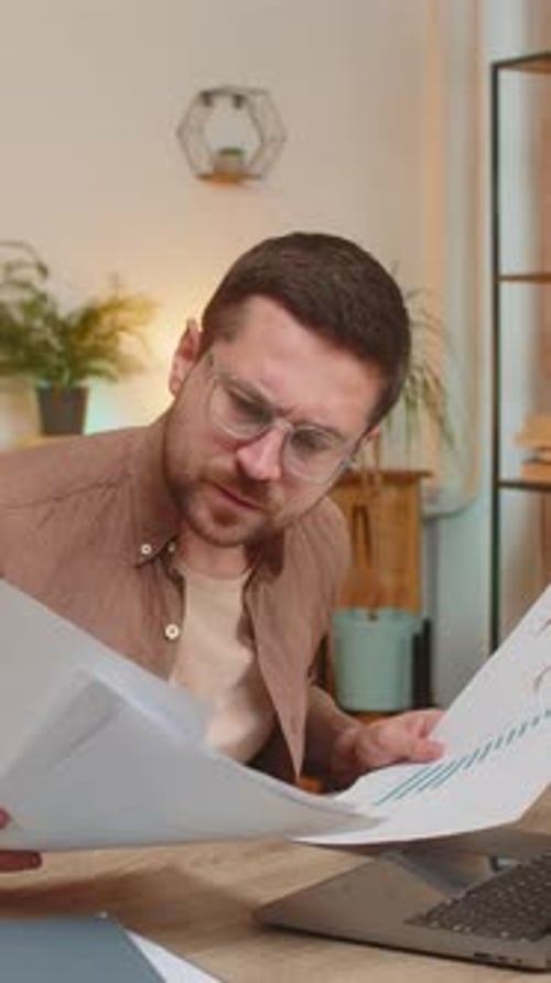 Stressed Upset Businessman with Laptop Looking at Unpaid Bank Debt Bills Sitting at Home Office Desk