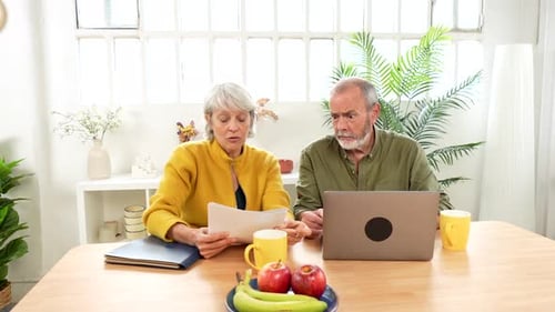 Older Couple Working Together at Home with Laptop