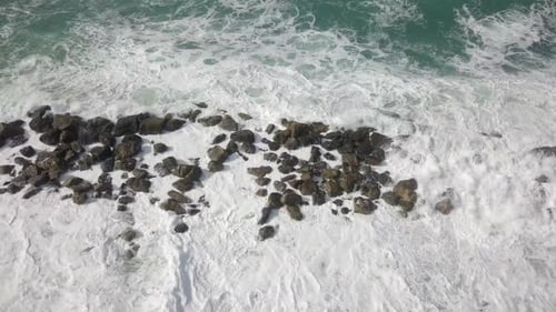 Aerial View of Waves Crashing Against Rocks