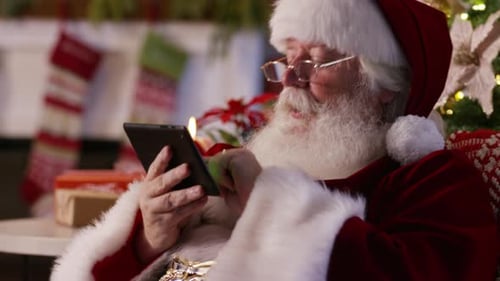 Santa Claus Using a Digital Tablet in Home Decorated for Christmas