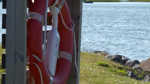 Slomo pan de aro salvavidas de anillo rojo en primer plano de hierba y mar ondulado