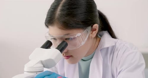 Focused woman works with a microscope in lab