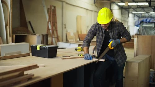 Carpenter sawing wood in workshop