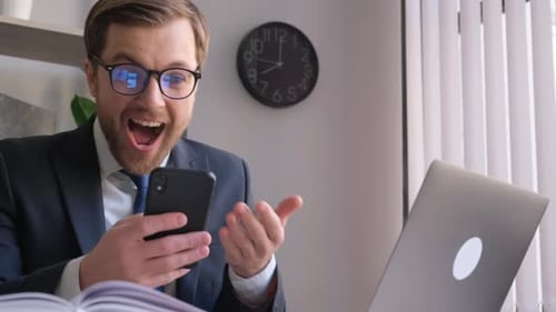 Crazy Businessman with a Smartphone in His Hands in the Office He Feels Happy and Energetic