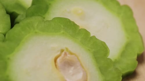Une gourde amère, un légume souvent utilisé comme ingrédient en cuisine, est posée sur une table en bois.