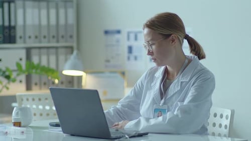 Woman Doctor Typing on Laptop in Office